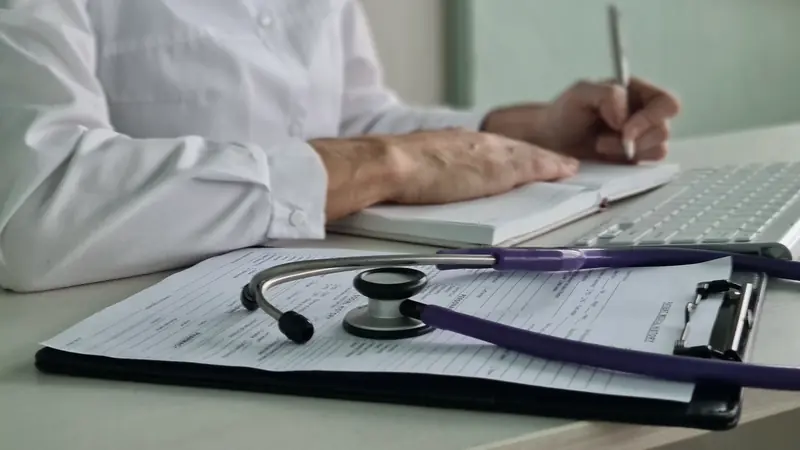 Ärztin mit Stethoskop und Patientenunterlagen am Schreibtisch