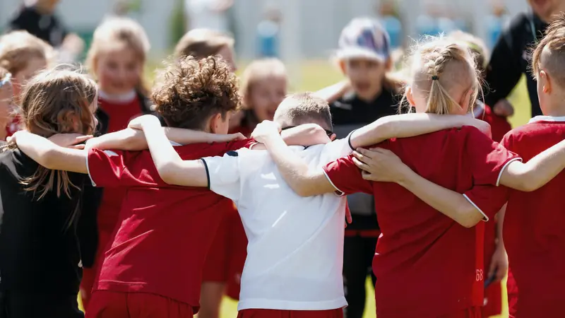 Jugendmannschaft im Kreis beim Teambuilding auf dem Sportplatz
