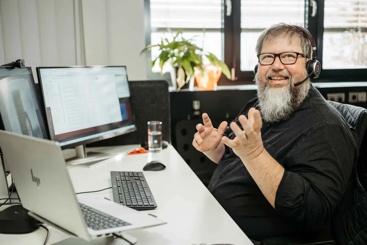 danubius-Mitarbeiter mit Headset im Beratungsgespräch am Schreibtisch
